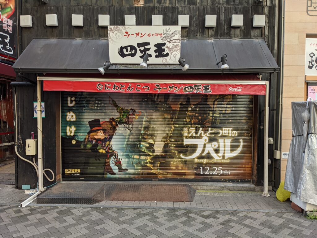 ラーメン四天王のシャッターに描かれた『えんとつ町のプペル』のビジュアルと「じぬけ。」の文字。