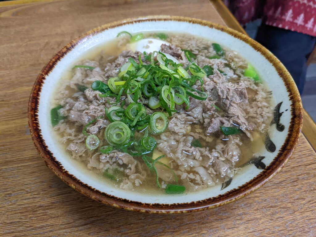 あつあつの牛肉うどん肉すい。たっぷりのネギと旨味がしみた牛肉が、あっさり出汁と調和している。