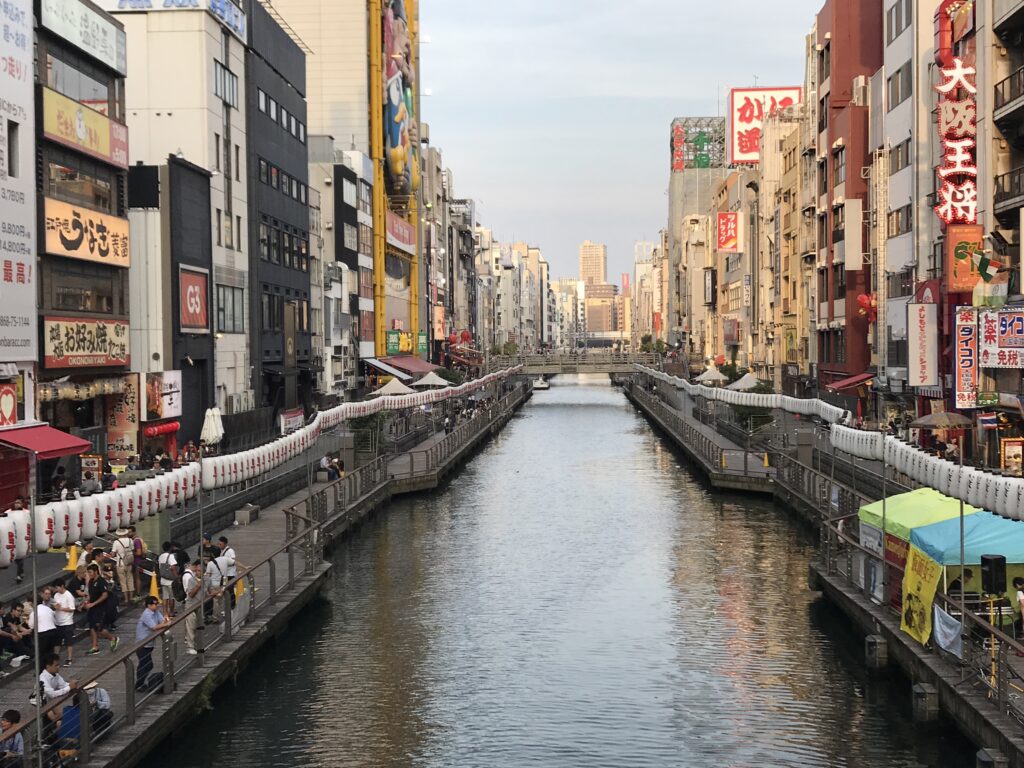 夕暮れの道頓堀川と両岸に並ぶ飲食店や提灯