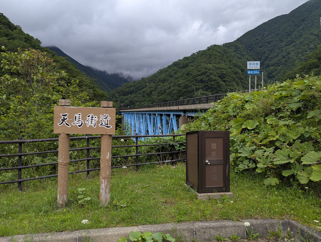 北海道浦河町、天馬街道沿いにある青い橋脚が特徴の翠明橋。手前に天馬街道の案内板と散水栓が写っている。