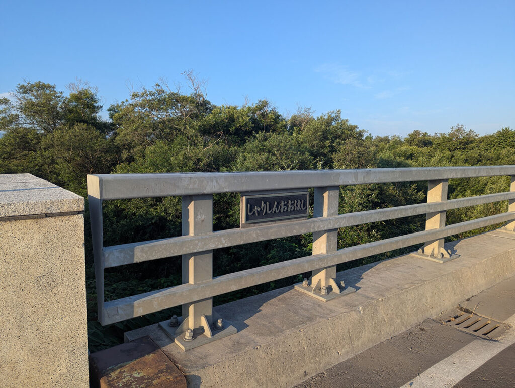 青空の下、新斜里大橋の欄干と橋名板