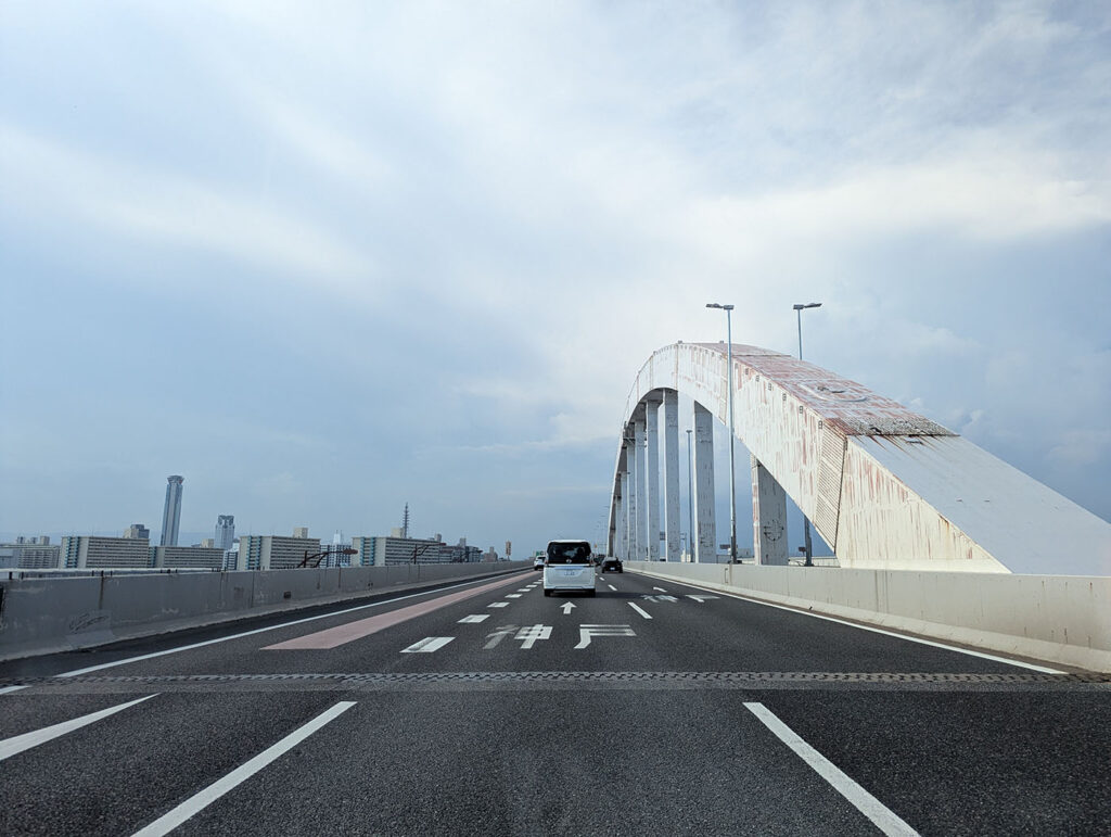 白い大きなアーチが特徴的な南港大橋。車道の先にアーチが弧を描き、都市の景観に溶け込んでいる。