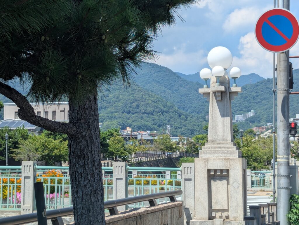 兵庫県芦屋市の業平橋。1925年竣工の鉄筋コンクリートT桁橋で、特徴的な球形照明を持つ親柱と緑色の欄干が印象的。背景には六甲山系が望める。
