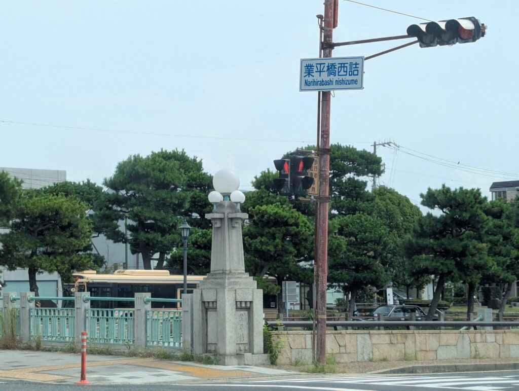 芦屋市業平橋西詰の街区表示板と橋の親柱。1925年竣工の業平橋は球形照明を持つ石造親柱と緑色欄干が特徴的で、現在も国道2号の重要な交通インフラとして機能している。